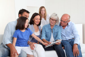 3-generation family sitting in couch with electronic tablet